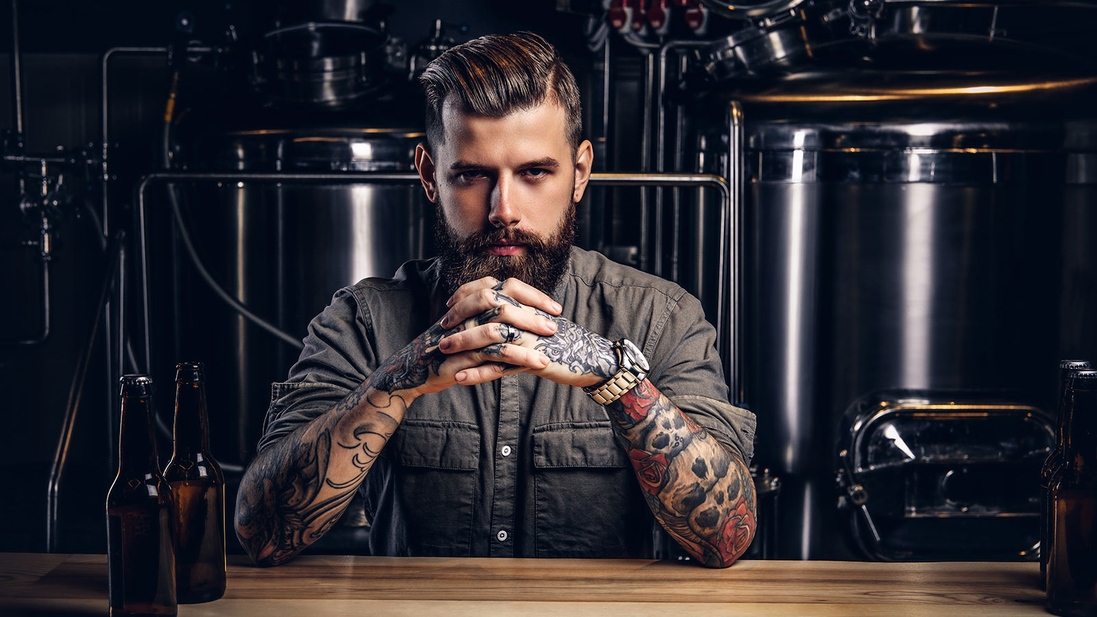 A tattooed man with a beard working at a brewery